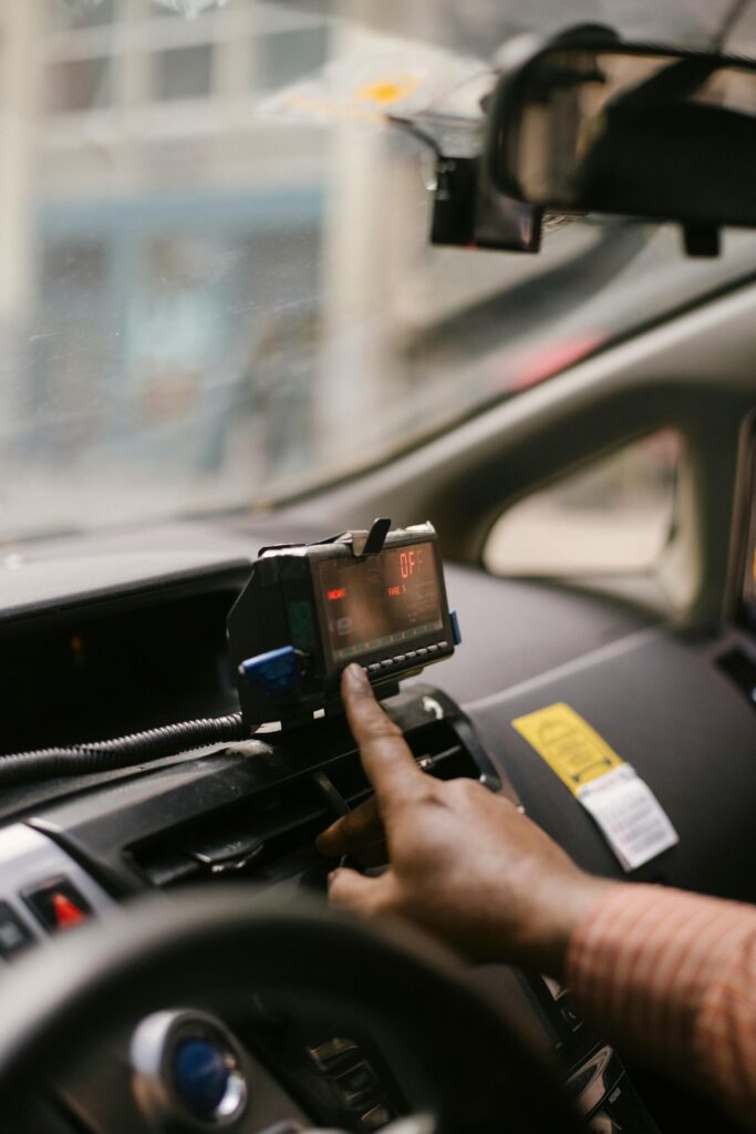 pexels-photo-5835463-5835463 A taxi driver adjusting the meter in the vehicle while taking a city ride.